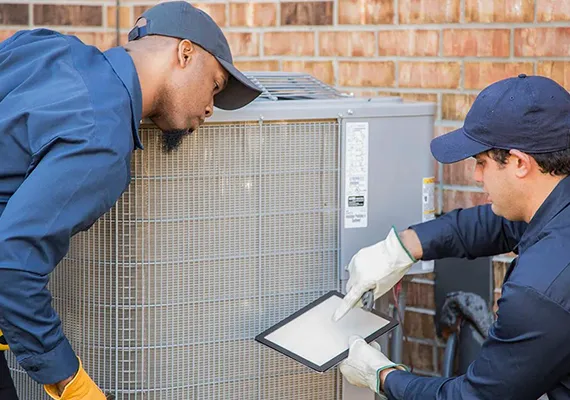 Two technicians collaborating on an HVAC maintenance task.