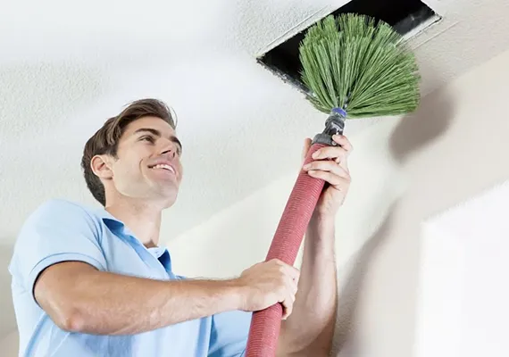 Technician cleaning air ducts with a duster, showcasing the benefits of professional air duct cleaning for better air quality and HVAC efficiency in Oglethorpe, GA.