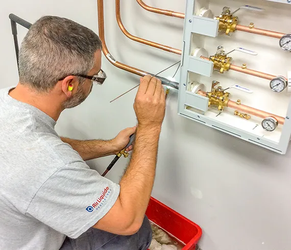 Experienced plumber inspecting and adjusting indoor gas pipe connections for comprehensive system services in Oglethorpe, GA.