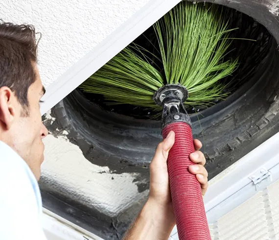 Specialist cleaning air ducts to remove dust and debris, showcasing efficient HVAC duct cleaning services in Oglethorpe, GA, for better indoor air quality.