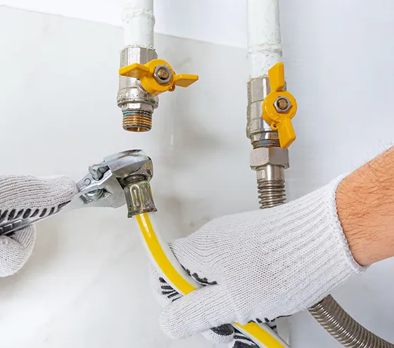 Technician repairing a white gas pipe using tools and gloves to ensure safe installation in Summerville GA.