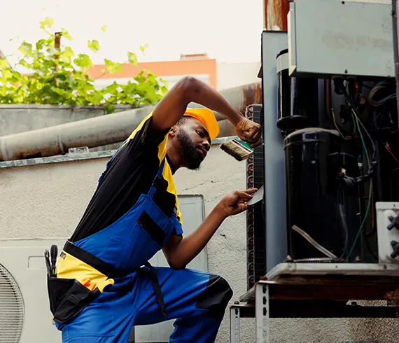 A technician performing maintenance on an air conditioning unit in a residential area.